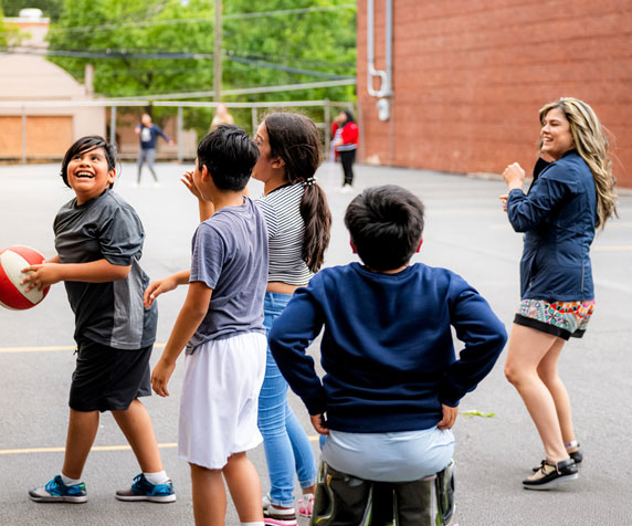 A counselor playing basketball with kids
