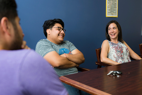 a group of people sitting at a table talking to each other